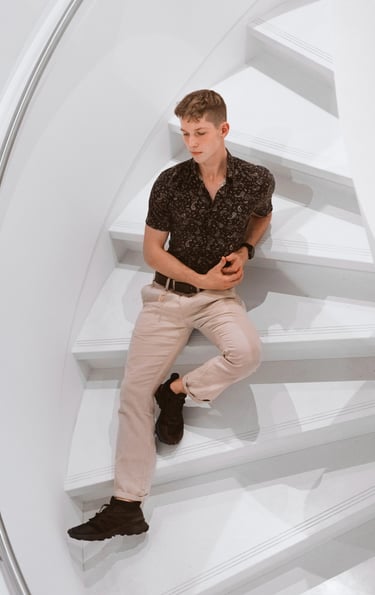 Portrait photo of a young man sitting on white stairs