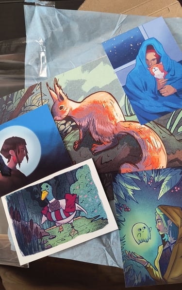A collection of colorful art prints featuring a red squirrel, a duck, and fantasy character illustrations.