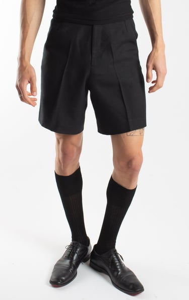 Model wearing black tailored dress shorts, knee-high socks, and leather oxford shoes.