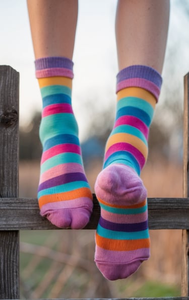 Due piedi con calze a righe in posizione innaturale sopra una staccionata