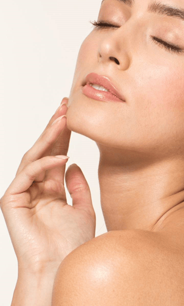 A woman with glowing, clear skin touching her face during a natural beauty and skincare routine PDRN