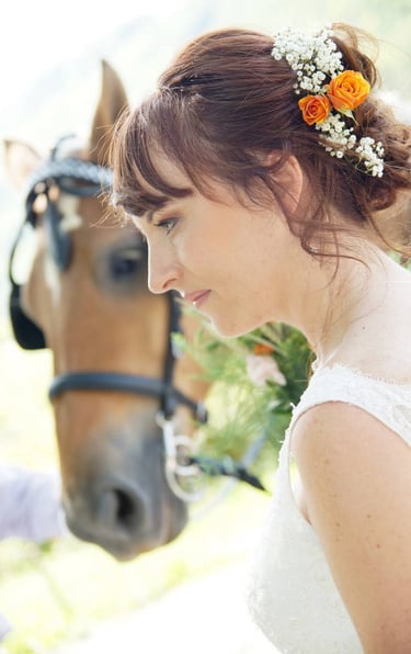 Portrait de mariée avec des fleurs dans les cheveux devant un cheval