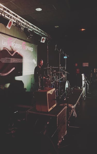 a man standing in front of a stage with a microphone and a guitar