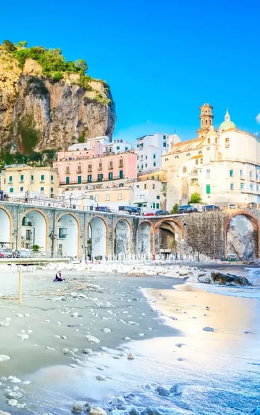 Colorful coastal buildings and arched bridges along the Amalfi Coast overlooking a sandy beach