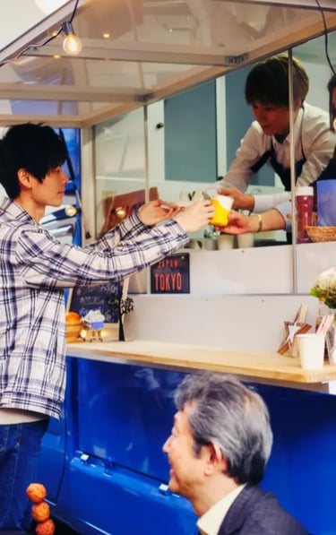 Customers ordering food at vibrant blue street food kiosk with string lights and Tokyo sign in urban