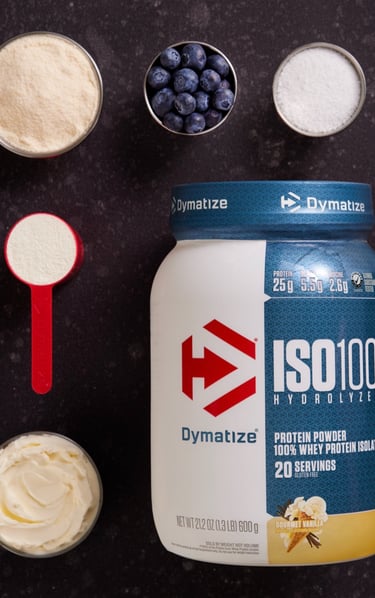 Dymatize ISO100 vanilla whey protein isolate powder with fresh blueberries and smoothie ingredients.