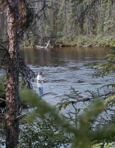 a man standing in a river with a fishing rod