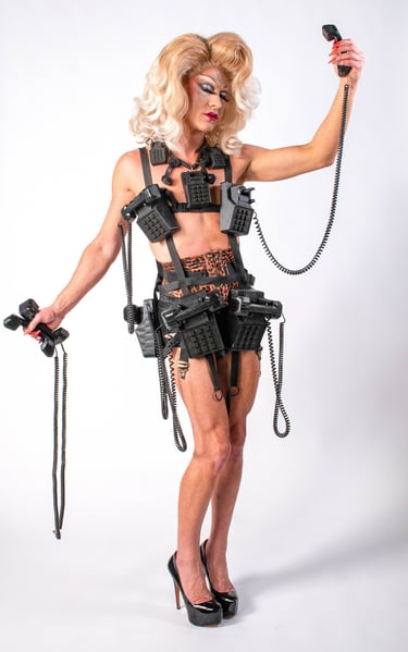 blonde drag queen in leapord print wearing a telephone themed outfit holding phone receivers/cords