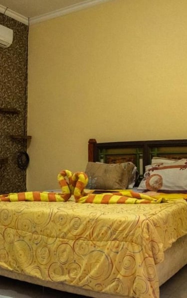 кровать с желтым постельным бельем и зеркалом наша комната в отеле Sunrise Lodge and Lovina Bali