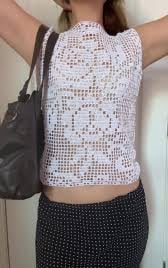 a woman in a white crochet top and black pants
