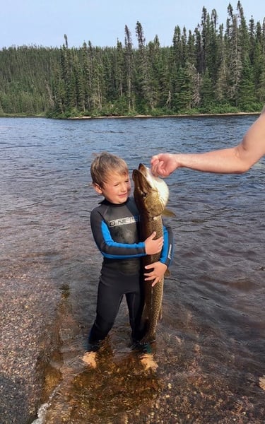a child holding a fish on a lake