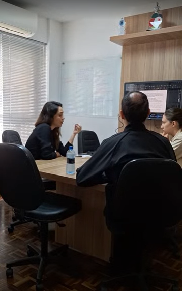 um mulher e um casal sentados em volta de uma mesa tendo uma reunião