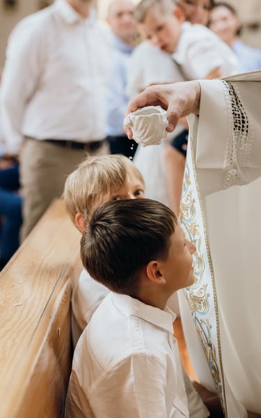 Krikštynų fotografija - kunigas šventina sėdinčius berniukus