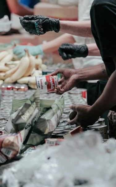 Unos voluntarios distribuyen alimentos enlatados y plátanos en un banco de alimentos