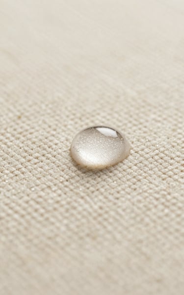 Macro close-up of clear liquid beading perfectly on a highly textured cream bouclé fabric, soft diffused side lighting highlighting the weave, minimalist and clinical luxury feel.