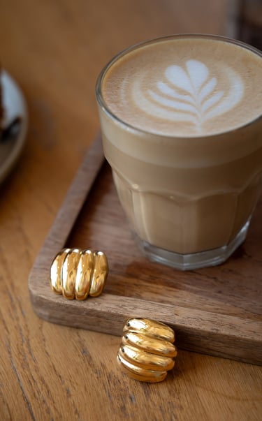 gold jewelries and a cup of coffee with a piece of cake on a tray