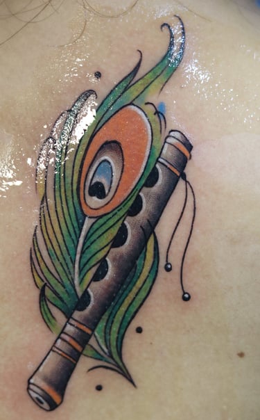 Flute with peacock feather watercolor fill by Dudo's Tattoos Hyderabad