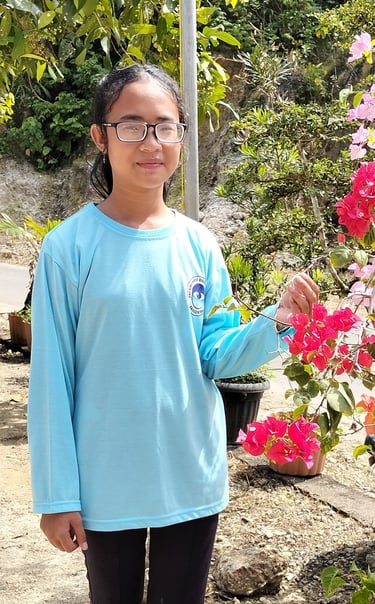 Febi berdiri sambil memegang bunga kertas
