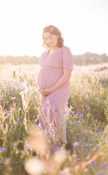 femme enceinte dans un champ de fleurs au coucher du soleil