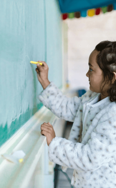 A girl writes on a chalkboard.