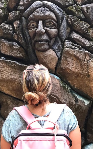 a woman with a backpacker in front of a stone wall