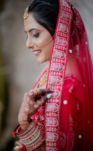 “Side-profile close-up of Indian bride holding red bridal dupatta, showing mehendi and bangles – bri