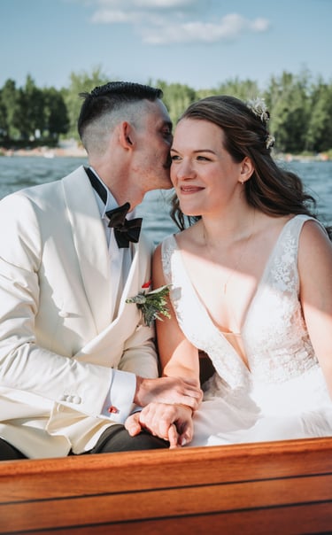 Une mariée et un marié partageant un moment romantique sur un bateau lors de leur mariage d’été.