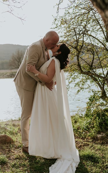 couple de mariés qui s'embrassent au bord d'un lac