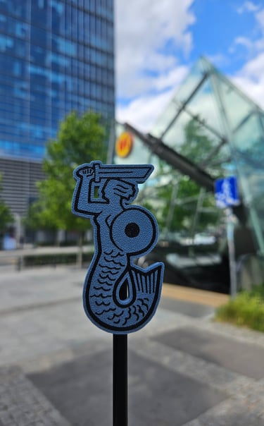 Niebieska syrenka na tle wejścia do Warszawskiego metra 