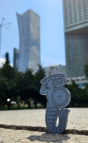 Magnes z syrenką z wieżowcami w centrum Warszawy w tle