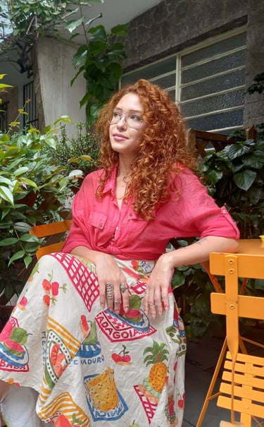 Sabrina Tibursky sentada de pernas cruzadas em frente a plantas