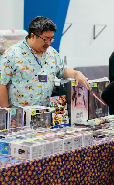 A vendor gestures to some of the nerdy items he has for sale.