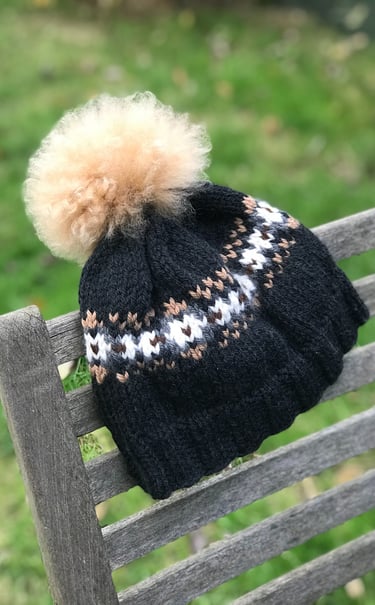 A woolly knit hat with a pom pom and stranded colour work