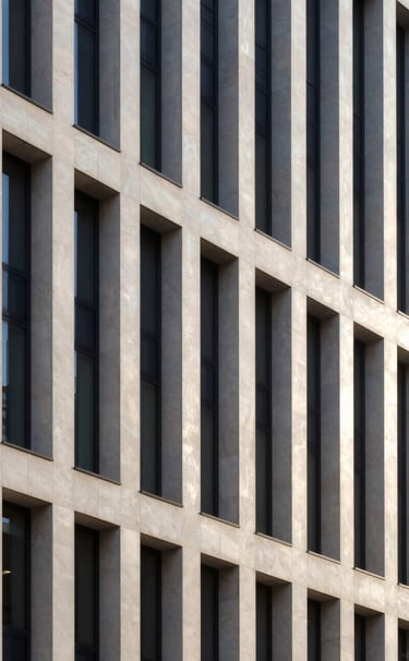 A minimalist architectural photograph of a sleek, modern financial building facade in an International / Western city. The stone is a pearlescent white, casting long, deep plum shadows in the golden hour light.