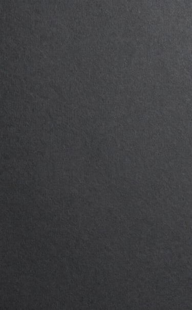 Minimalist photography of a high-quality charcoal paper texture in dark grey tones, uniform lighting, sophisticated and clean composition, European / Spanish aesthetic.