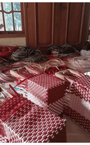 Finishing the woven structure of a handmade bag using recycled plastic strips at Craftvitas Indonesia.