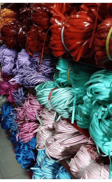 Bundles of multi colored recycled plastic weaving strips neatly stored and ready for handmade woven bag production.