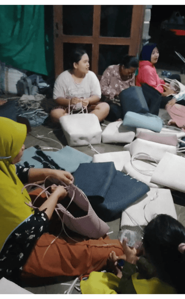 Group of artisans crafting handmade woven plastic bags together at Craftvitas Indonesia production area.