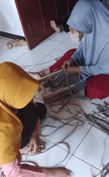 Handmade jali jali woven bag frame being prepared by artisans using recycled plastic weaving strips.