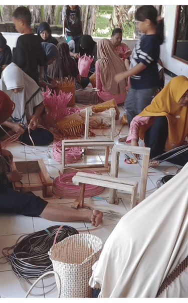 Artisans finishing colorful jali jali plastic woven bags by hand at Craftvitas Indonesia workshop.
