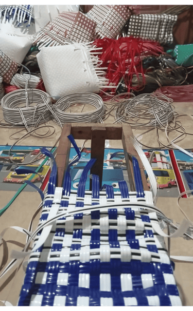 Shaping the base of a yellow and white handmade woven bag using recycled plastic weaving strips at Craftvitas Indonesia.