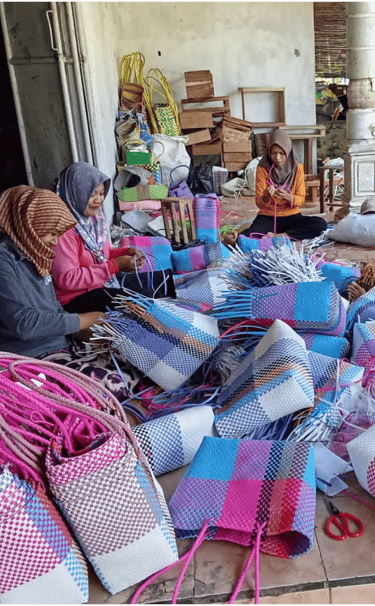 Artisans shaping and adjusting handmade plastic woven bags during production at Craftvitas Indonesia.