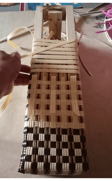 Ongoing weaving process of a blue and white handmade plastic woven bag at Craftvitas Indonesia workshop.