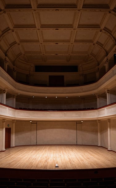 A wide angle shot of a grand 19th-century Spanish concert hall stage, elegant architecture, muted sand and deep taupe colors, professional photography, Southern European / Spanish cultural heritage.