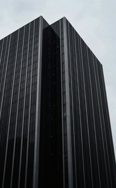 A minimalist close-up of architectural details of a modern skyscraper in a North American city, sharp angles, deep black shadows against a bright light gray sky, focusing on clean geometric lines.