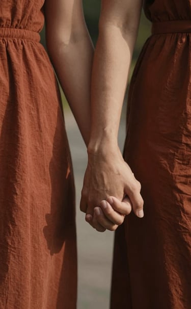 A close-up, intimate photograph of a couple's hands gently intertwined while walking. Soft, warm sunlight filters through, highlighting textures of their clothing in Terracotta (#C0766B) and the soft skin tones. Cinematic, high-contrast lighting with a focus on connection and emotion.