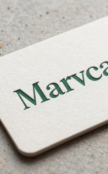 Close-up macro photography of a minimalist branding project. An off-white business card with deep dark green embossed typography. The background shows a textured light gray stone surface. South American / Brazilian professional aesthetic, soft morning light.