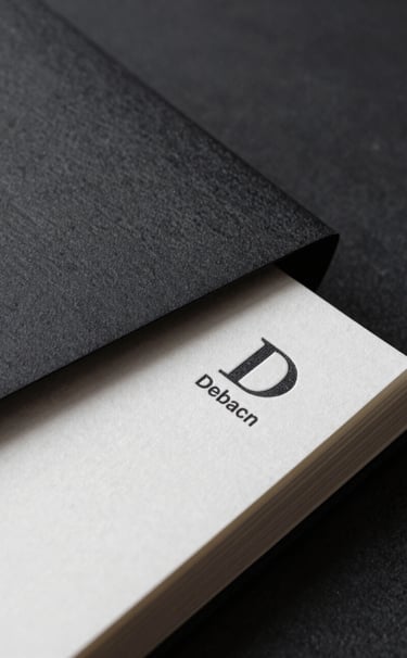 A deep charcoal black and pure white high-contrast close-up of premium textured stationery, showcasing a debossed logo on thick paper, sophisticated and professional.
