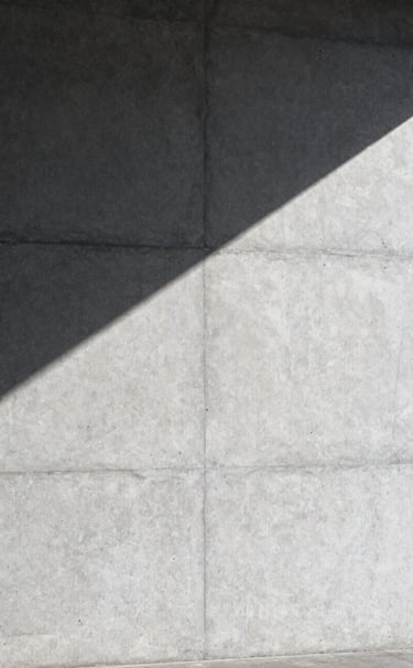 Large-scale architectural photography of a concrete wall in Stockholm. A single sharp shadow cuts across the surface. Minimalist, clean lines, professional composition with silver and dark gray tones.