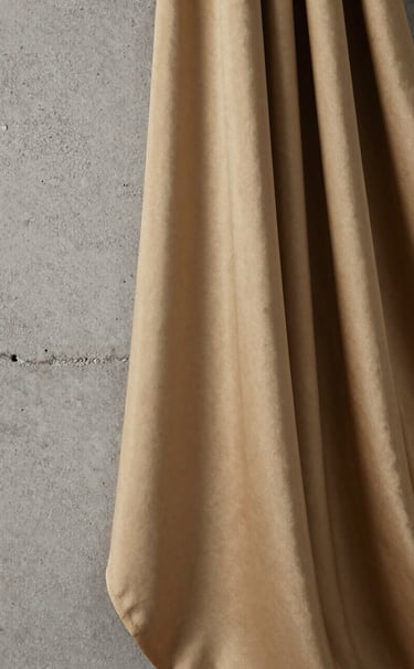 Close-up photography of a set design detail featuring raw concrete textures juxtaposed with flowing silk fabrics in muted gold. Sharp focus on the interplay of light and texture. Elegant and avant-garde style, professionally lit in a French studio.